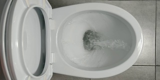慢镜头:水在一个白色的厕所里流动