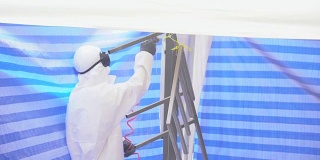 慢镜头:一个戴着防护面具、穿着工作服的成年人正在粉刷家具