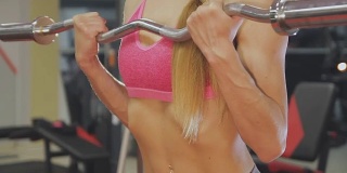 女人在健身房的一个酒吧里训练。漂亮的身体
