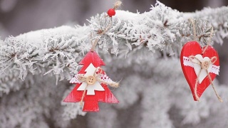 红色的木制圣诞玩具心和冷杉树挂在下雪的圣诞树的树枝上。高清视频运动视频素材模板下载