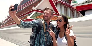 一对游客情侣在泰国的泰国寺庙用智能手机自拍