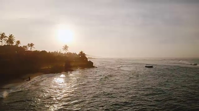 不可思议的航拍美丽的日落海岸线，海浪反射夕阳，到达异国情调的热带海岸