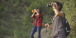 年轻女性在山林中徒步旅行时使用双筒望远镜。