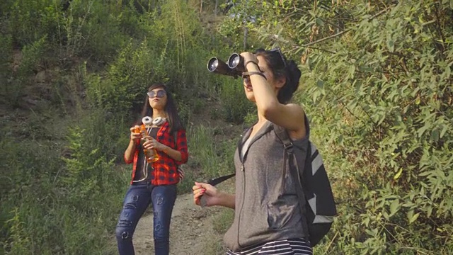 年轻女性在山林中徒步旅行时使用双筒望远镜。