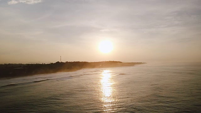 无人机在美丽的日落海洋上空飞行。令人惊叹的空中全景夕阳反射，海浪到达海岸