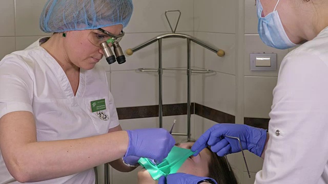 一名妇女在牙科诊所接受牙科治疗以补牙洞。牙科修复与复合材料聚合紫外光与激光。