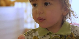 小男孩一边盯着镜头一边享受棒棒糖。孩子吃糖果，糖果，糖