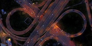 无限高速公路立交桥鸟瞰图，繁忙的城市交通在夜间高速行驶