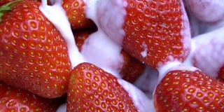 成熟红草莓与酸奶混合的慢动作视频