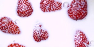 红熟草莓落入牛奶的慢动作视频捕捉