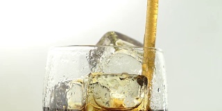 苏打水装在玻璃杯里，冰通过管子喝。白色背景。近距离