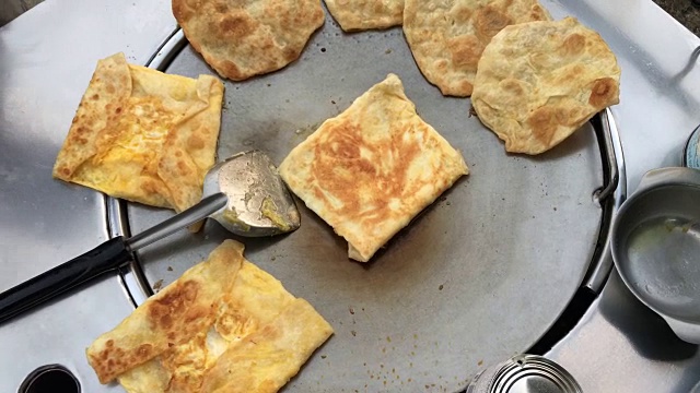 在泰国的市场上做异国风味的泰国煎饼，马来西亚烤饼。用煮熟的油在热的金属锅上煎蛋。泰国小吃。泰国甜点。