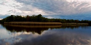 日落时，风暴云在湖面上移动。彩色天空的蓝色，黄色和橙色的日出在全高清高清视频