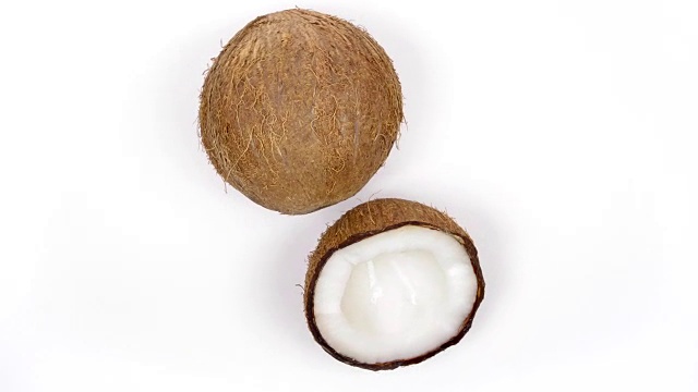 一个完整的椰子和美味的果肉旋转在白色孤立的背景。Loopable无缝