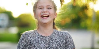 特写肖像的金发欧洲小女孩微笑与所有她的牙齿。阳光明媚的午后，快乐的孩子让每个家长感觉良好。孩子气的微笑是积极情绪的源泉