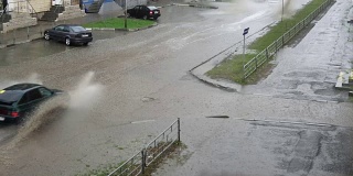 汽车在雨中行驶在被洪水淹没的道路上，慢镜头。