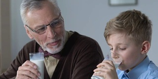 学校男孩和爷爷一起在早上喝牛奶，一家人吃早餐