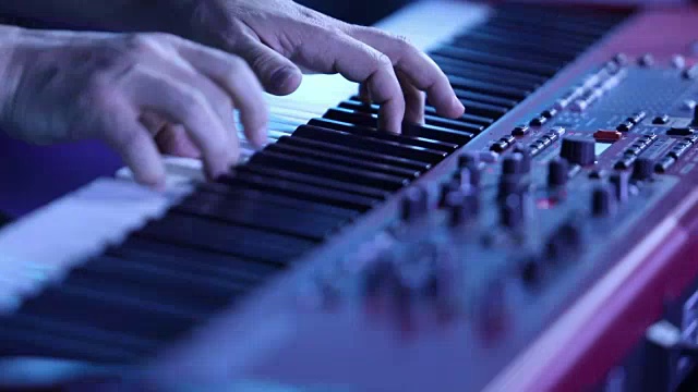 弹奏电子钢琴的音乐家，弹奏电子钢琴的演员，用键盘合成器弹奏钢琴琴键。音乐家在音乐会舞台上演奏乐器。合成器