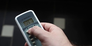 使用空调遥控器调节室内温度。在炎热的夏天，空调和远程控制