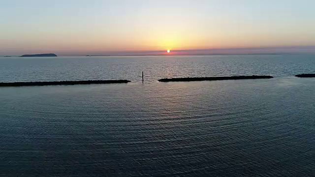 无人机飞，防波堤的石头在夕阳的海面上