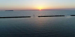 无人机飞，防波堤的石头在夕阳的海面上