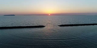 无人机飞，防波堤的石头在夕阳的海面上