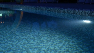 游泳池的夜间照明会改变颜色。酒店室外游泳池配有冷水视频素材模板下载