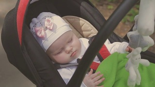 美丽的女人在公园里推着婴儿车和她的小女儿散步视频素材模板下载