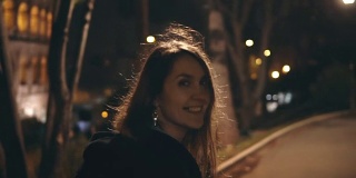 一个快乐的年轻女子在意大利罗马斗牛场附近奔跑着，她在傍晚笑着回头看。慢动作
