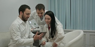 一组医生在医务室用平板电脑看一些有趣的东西
