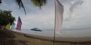 空旷的沙滩上挂着五颜六色的旗帜和遮阳伞。跟踪拍摄