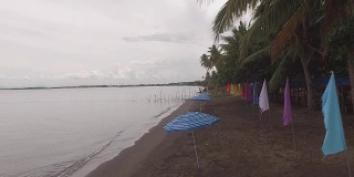 空旷的沙滩上挂着五颜六色的旗帜和遮阳伞。无人机空中
