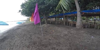 空旷的沙滩上挂着五颜六色的旗帜和遮阳伞。跟踪拍摄