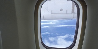 在飞机上透过窗座观看多云的蓝天。