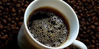 黑咖啡倒进白杯子里，堆在一堆烘好的咖啡豆上