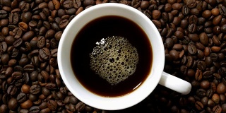 白杯子里的黑咖啡，堆在一堆烘好的咖啡豆上
