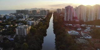在夕阳的映衬下，空中拍摄的巴拉达蒂茹卡的马拉潘迪运河。一边是高耸的住宅楼，另一边是海滩。巴西的里约热内卢