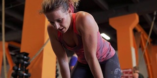 疲惫的健身女性在健身房锻炼后倾身深呼吸