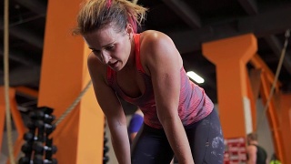 疲惫的健身女性在健身房锻炼后倾身深呼吸视频素材模板下载
