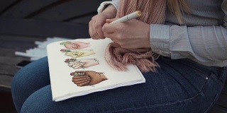 年轻的女学生正用毛笔勾勒着明亮的画面，手的特写