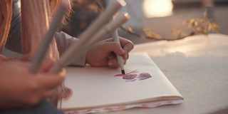 女孩正在户外公园里画画，用记号笔和图片的手的特写