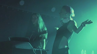 夜店里，两个年轻漂亮的女DJ在调音台播放音乐。在一群不认识的人的背景下。慢动作视频素材模板下载