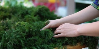 女性的手在超市挑选绿色蔬菜。