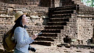 亚洲女子背包旅行者使用地图古塔寺庙泰国建筑在素可泰，泰国。节日假期的概念。旅行的生活方式视频素材模板下载