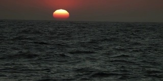 从一艘船的舷窗望去，是平静的日落的海面