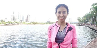 慢动作——穿着健身服的亚洲美女正在用智能手表听音乐，在公园跑步后打电话。有吸引力的健康女性慢跑。