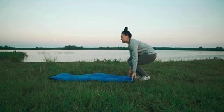 美丽的女人准备做早上的瑜伽练习。拿着蓝色瑜伽垫的女孩