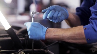 在汽车修理厂用扳手修理汽车的技工视频素材模板下载