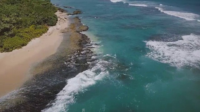 无人机俯瞰异国情调的度假海滩，小船，热带树木，泡沫的海浪撞击美丽的海岸