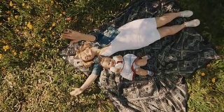 母亲和女儿躺在草坪上。幸福的母亲和童年